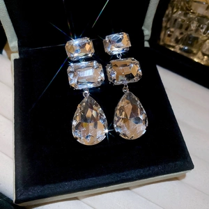 Close-up of tiered crystal drop earrings with square and pear-shaped stones in a box