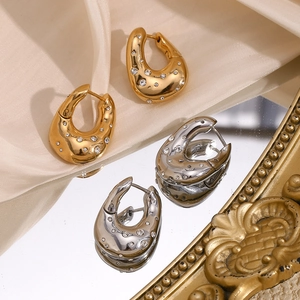 Detail of twisted 18K gold and silver hoop earrings with sparkling rhinestones on mirror