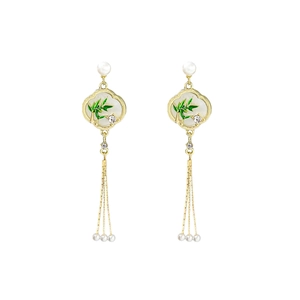 Detail of vintage bamboo tassel earrings with green enamel and white pearls