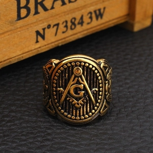Classic golden stainless steel Freemason ring with G symbol on a black leather surface