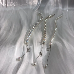 Macro view of white aurora pearls and 14k gold-filled clasps on luxurious white silk cloth