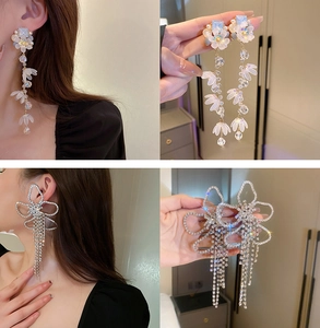Detalle de pendientes de flores con perlas y pendientes de lazo con pedrería puestos