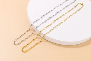 Close-up of minimalist gold and silver link chains on white round display platform