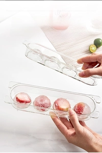 Detail of four-hole spherical ice mold with strawberry ice balls inside a clear tray