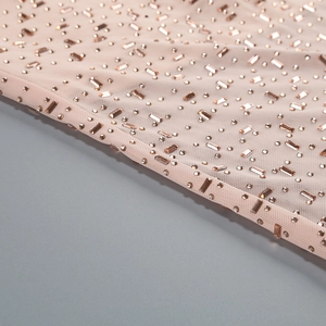 Gros plan détaillé de strass champagne sur un tissu en maille fine rose-orange