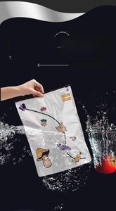 Reusable food storage bag with slider seal and vegetable patterns being rinsed in water