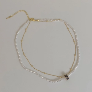 Collier double rang doré avec perles et un pendentif cylindrique en cristaux noirs
