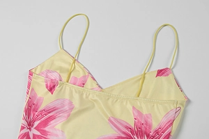 Detailed macro view of yellow satin floral dress with pink lilies and fine shoulder straps