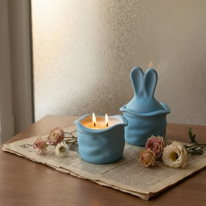 Matte blue bunny ear ceramic candle jar with artistic ripple texture and warm flame