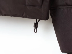 Close-up of adjustable drawstring and toggle on dark brown hooded jacket hem