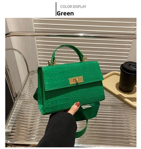 Detail of green crocodile embossed crossbody bag with gold twist lock and wide strap