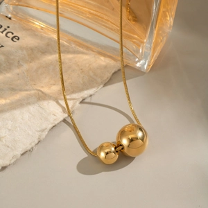 Minimalist gold snake chain necklace featuring double sphere pendants in polished finish