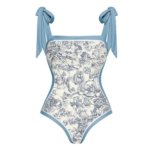 Detail of light blue floral swimsuit featuring adjustable bow straps and floral print