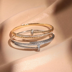Detailansicht ineinandergreifender Nagelarmbänder in Gold und Silber mit Zirkonia-Mikropavé