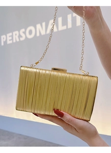 Detail of elegant gold pleated evening clutch bag with delicate metal chain strap