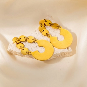 Elegant gold earrings with stacked metal discs on a white stone and silk background