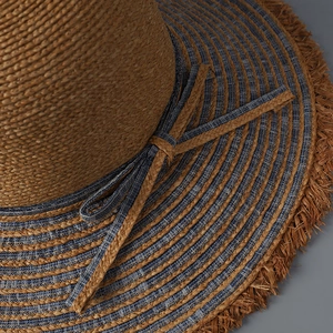 Close-up of denim and raffia straw stitching with decorative bow and frayed edges