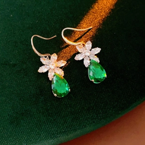 Boucles d'oreilles fleur dorées avec zircon vert en forme de poire sur velours vert
