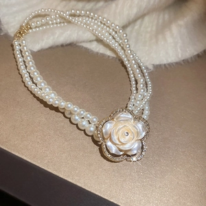 Detailed close-up of multi-layer pearl necklace with a rhinestone floral shell pendant