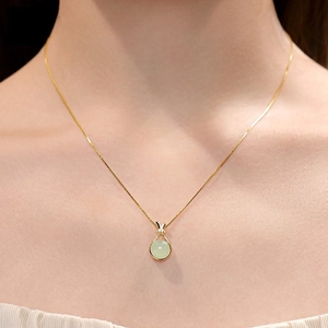 Minimalist gold titanium steel necklace with a light green jade pouch pendant on a woman