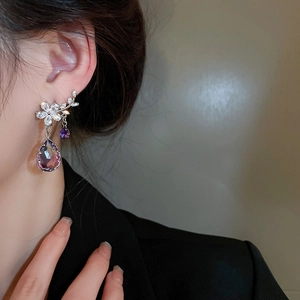 Detail of silver branch earrings with purple crystal drop and floral diamond accents
