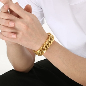 Close-up of a masculine 18mm wide golden Cuban link chain bracelet on a male model's wrist