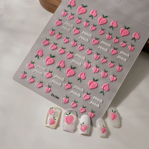 Macro shot of cute peach-themed nail art stickers and peach patterns on false nails