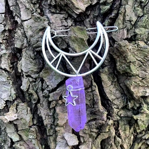 Silver crescent moon hair clip with purple crystal point and star charm on bark background