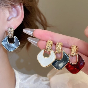Detail view of acrylic rhombus earrings in four colors with gold metal accent