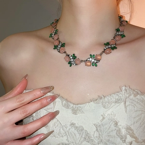 Detail of floral crystal necklace with pink resin bead worn on model's neckline
