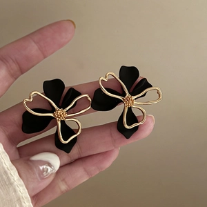 Detail of double-layer hollow flower studs with black matte petals and gold metal trim