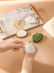 Cloud-shaped travel soap flakes container in amber and green with hands showing usage