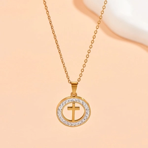 Detailed macro view of a gold circular necklace with hollow cross and small zircon stones