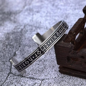 Vintage Viking Rune open bangle in silver stainless steel on a dark wooden display stand