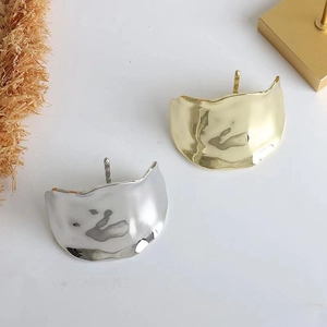 Macro shot of gold and silver irregular textured metal hair clips with lava surface finish