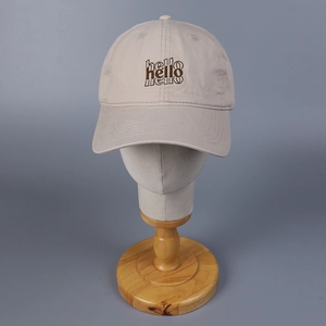 Detalle de gorra beige de algodón lavado con triple bordado Hello en la parte frontal