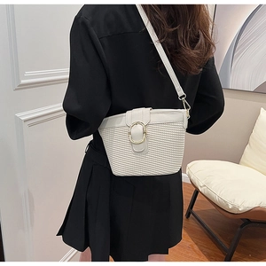 Detail of cream crossbody bag with woven texture and gold buckle on black dress