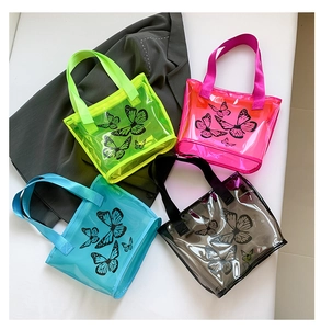 Flat lay of colorful PVC tote bags with butterfly prints on a grey blazer background