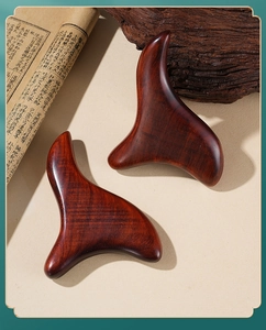 Macro shot of sandalwood gua sha tools on vintage books for meridian acupressure therapy