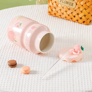 Pink peach ceramic mug with wavy lid and glass straw on a minimalist white grid tablecloth