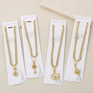 Detail of four golden stainless steel necklaces with various pendants on white cards