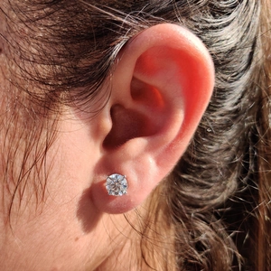 Macro shot of 925 silver moissanite stud earring with classic four-prong setting on ear