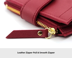 Detail of burgundy leather wallet featuring a smooth golden zipper and leather puller