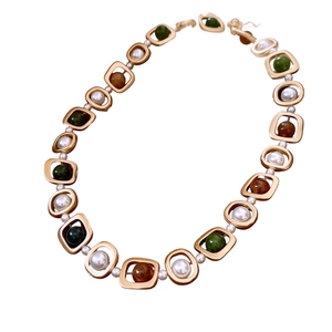 Collier vintage doré avec perles et billes vertes disposé dans un design circulaire chic