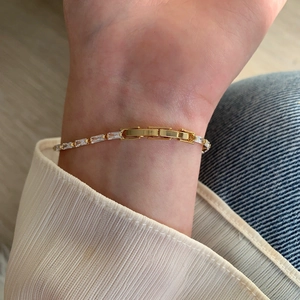Close-up of a gold bracelet with rectangular AAA zircons worn on a female wrist