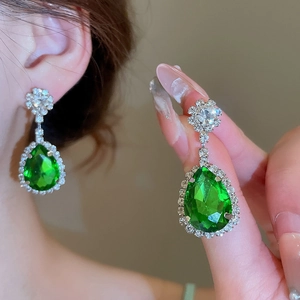 Dettaglio di orecchini in argento con grandi gemme a goccia verdi e piccoli strass