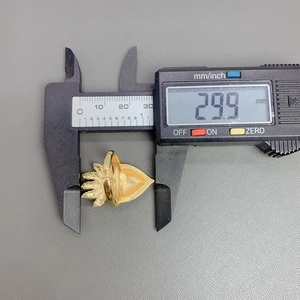 Digital caliper measuring the 29.9 mm width of a gold heart wing ring on gray background