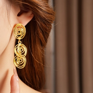 Close-up of vintage golden spiral tiered earrings on a model in retro court style