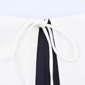 Detail of college style dress featuring contrast color stitching and bow tie neck design