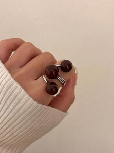 Close-up of triple sphere open ring in silver and brown worn on hand with knit sleeve